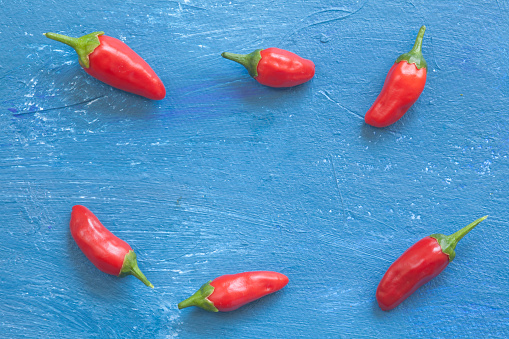 A view red peppers laying on  blue background. Aranged in a row.