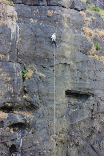 A rappeller on his way to climb down the hill with help of rope and equipments in Duke Nose, India.