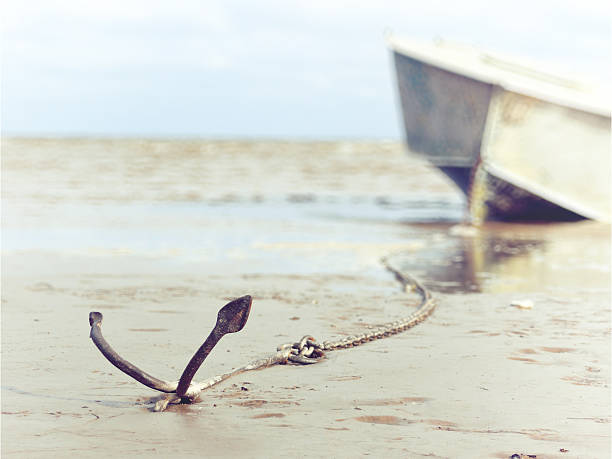 anchored on the shore with boat anchored on the shore with boat in the background anchor chain stock pictures, royalty-free photos & images