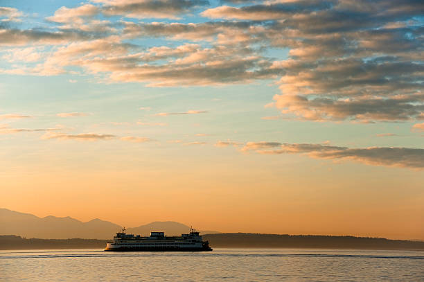 Ferryboat at Sunset. A Washington state ferry crosses Elliott Bay to Bainbridge Island during the commute hour during  lovely sunset and dramatic sky. bainbridge island stock pictures, royalty-free photos & images