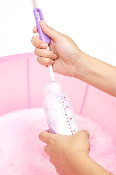 mother's hand cleaning, washing baby milk bottle