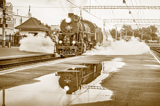 Vintage style image of the retro steam locomotive standing on the station.