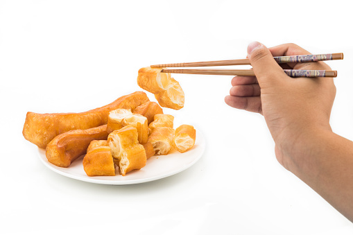 Chopsticks reaching for a piece of You Tiao, or fried bread stick