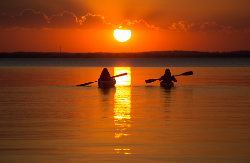 A beautiful sunset evening, two good friends, synchronized rowing, on the Bay of Green Bay in Wisconsin.  These two kayaks were sitting on the mirror like water watching the sun drop in the western sky.