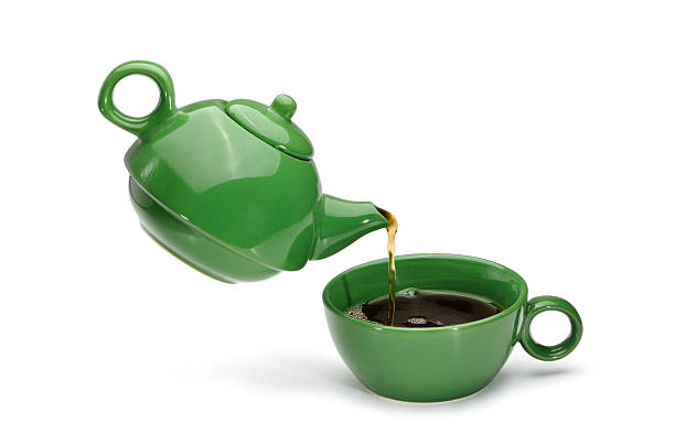 istock Green teapot pouring tea into a green cup 488277585