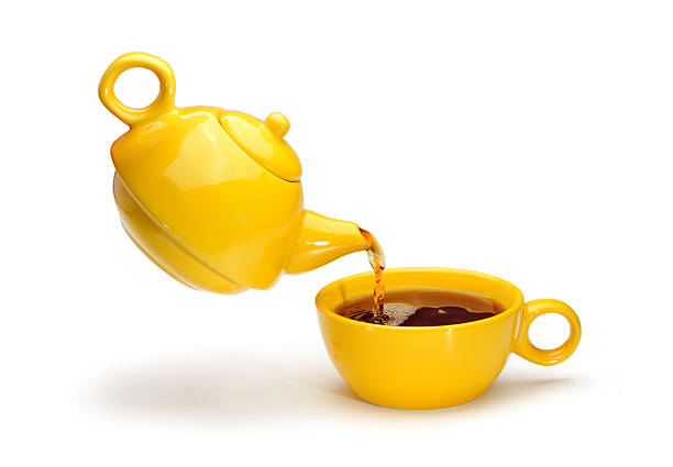 istock Yellow teapot pouring tea into a yellow cup 488278021