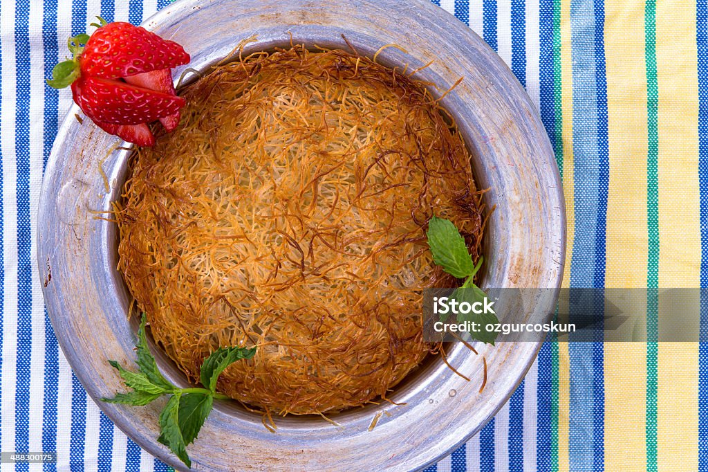 Kunefe, Turkish Dessert on a picnic cloth Turkish dessert kunefe isolated on a picnic cloth with mints and sliced strawberry Baked Pastry Item Stock Photo