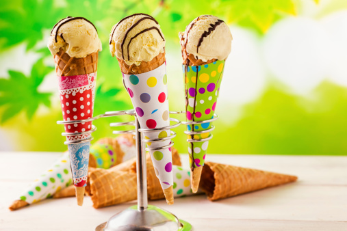 Vanilla ice cream cones with chocolate sauce. This frozen dessert is made from dairy products, such as milk and cream. They can be combined with fruits and other ingredients and flavour.