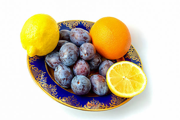 ciruelas y naranjas, limones en una placa. - plum yellow eating beauty and health fotografías e imágenes de stock