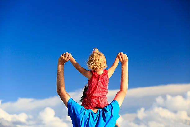 istock father and little daughter on shoulders play at sky 488312156