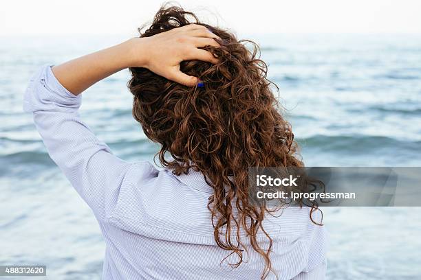 Young Woman In Shirt Looking At The Sea Stock Photo - Download Image Now - Curly Hair, Beach, Wave - Water