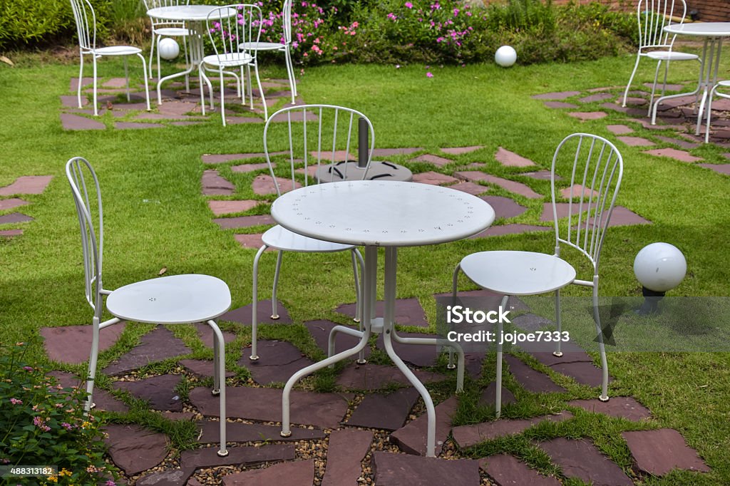 White steel table and chairs outside White steel table and chairs outside in a garden on green    2015 Stock Photo