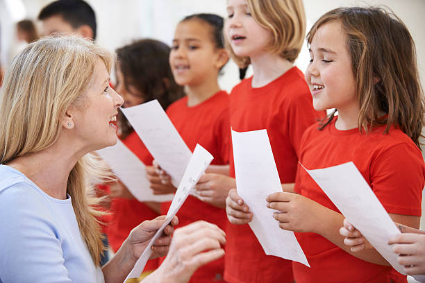 istock Children In Singing Group Being Encouraged By Teacher 488313484