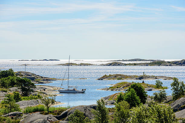 Moored sailboat and skerries in the sun Sailboat moored at small rocky island in the outer part of the archipelago of Stockholm, Sweden archipelago stock pictures, royalty-free photos & images