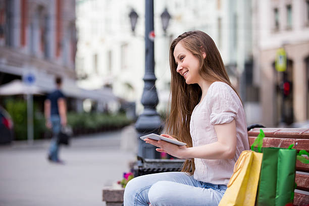 istock Young l woman sitting on a bench with digital tablet 488316058