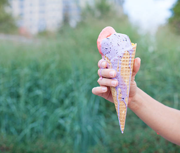 istock Beautiful woman's hand holding a colorful ice-cream cone. Close up 488317830