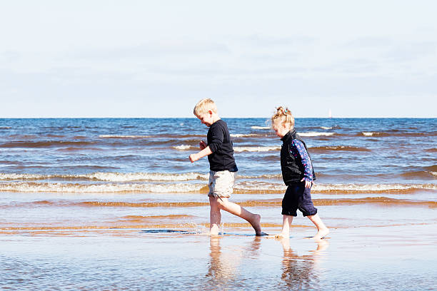 istock Boy and girl walking on beach 488320424