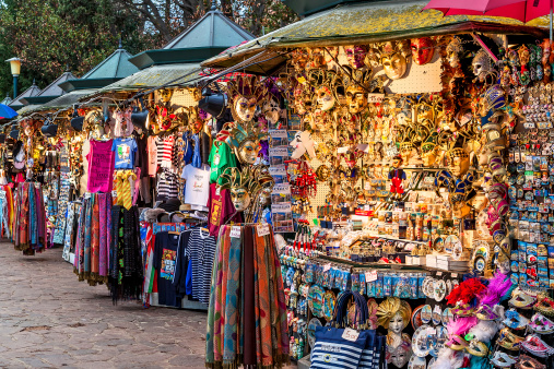 Venice, Italy - November 13, 2012: Outdoor vendor stands - profitable and popular form of sales traditional souvenirs and gifts such as masks, magnets, clothes and travel guides to a huge number of tourists visiting Venice, Italy.