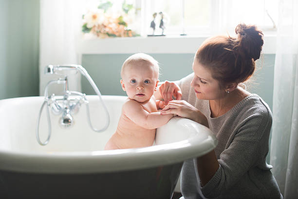Mom giving baby bath stock photo