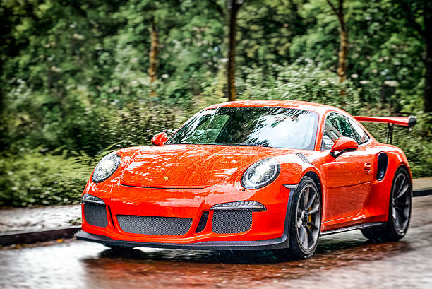 Zwolle, The Netherlands - September 5, 2015: Orange Porsche 911 GT3 RS sports car driving on the street in the city of Zwolle in the rain.