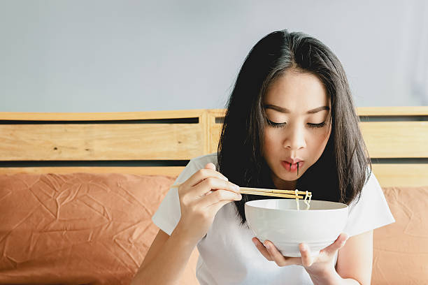 istock Asian girl is eating noodle. 488361744