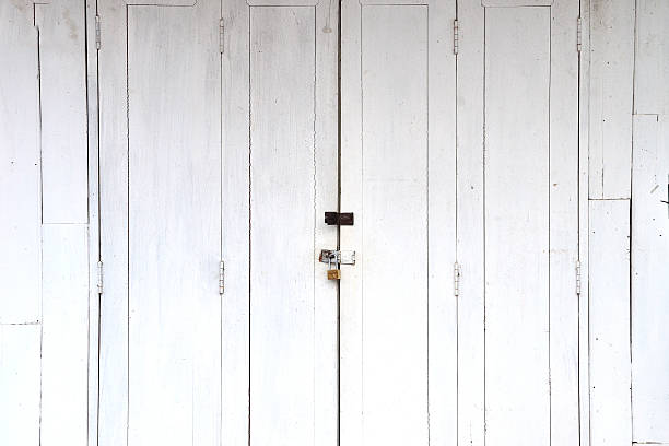 istock Old metal handle and padlock on white wooden door. 488361912