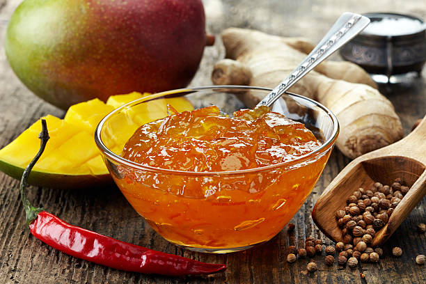 bol de chutney de mangue sur table en bois - gelatin dessert orange fruit marmalade photos et images de collection