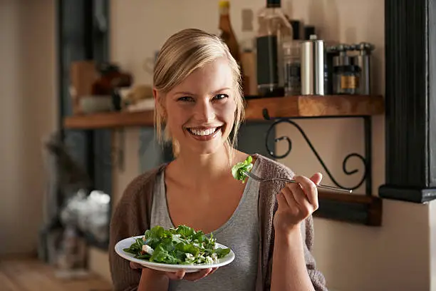 Portrait of an attractive young woman eating a salad in her kitchen
