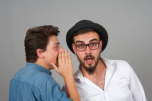 istock Young man whispering something his friend's ear 488379644