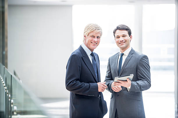istock Two smiling businessman with digital tablet 488385070