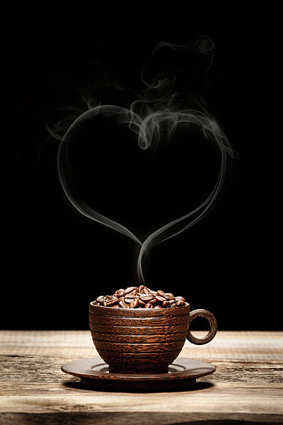 Wooden cup with beans and heart-shaped smoke Wooden cup with beans and heart-shaped smoke on dark background decaffeinated stock pictures, royalty-free photos & images