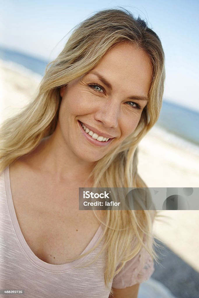 The perfect spot to get away from it all Head and shoulders portrait of an attractive young woman standing on a sunny beach Beach Stock Photo