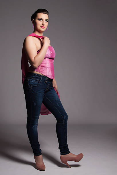 Young woman in pink corset, jeans, high heels with scarf stock photo