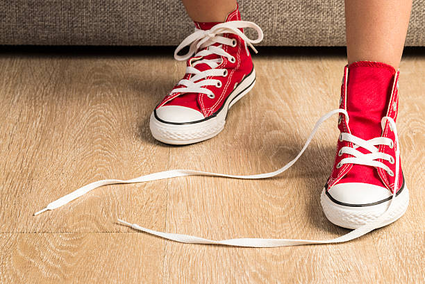 Girl wearing a pair of red sneakers Little girl wearing a pair of red sneakers at home. A sneaker is untied kid tripped stock pictures, royalty-free photos & images