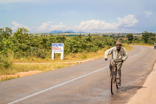Pilila, Zambia - March 31, 2015: Man riding bicycle on the road in the countryside of Zambia.
