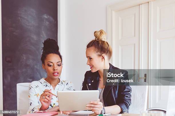 Two Women Working On Digital Tablet In An Office Stock Photo - Download Image Now - Social Media, Manager, Persuasion