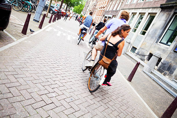 Cycling people in Wallen of Amsterdam Amsterdam, The Netherlands - August 9, 2015: Capture of cycling people in Wallen of Amsterdam. Rearshot of people. At right side a man is cycling wth woman in back. wellen stock pictures, royalty-free photos & images