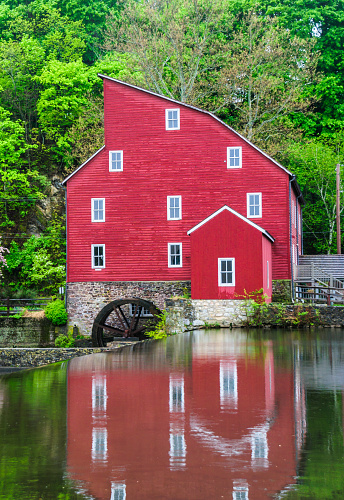 An old red mill is reflected in the mill pond above the  dam in Clinton, New Jersey.