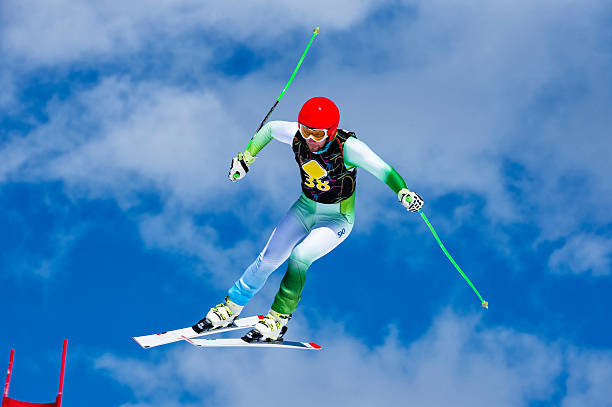 Front view of young male skier at straight downhill race against the blue sky