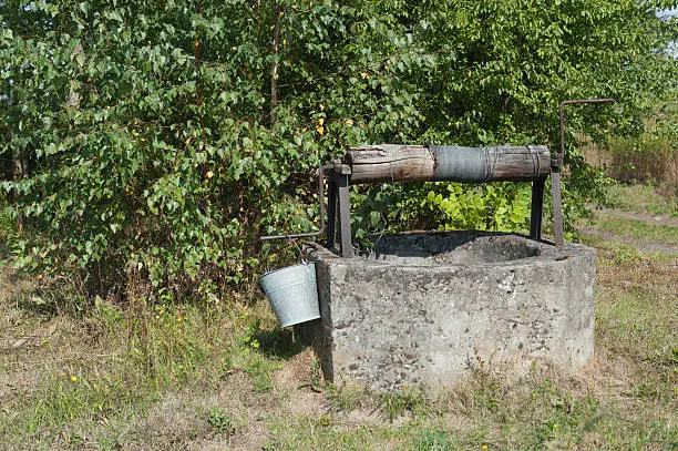Old draw well with a bucket hanging on the crank-handle