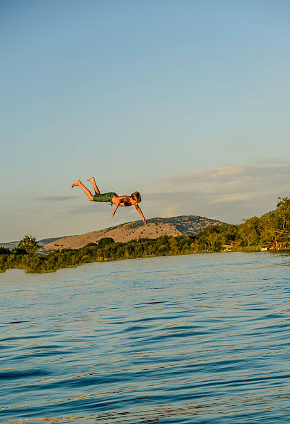 istock Little boy jumping in the river from the old krane 488414084