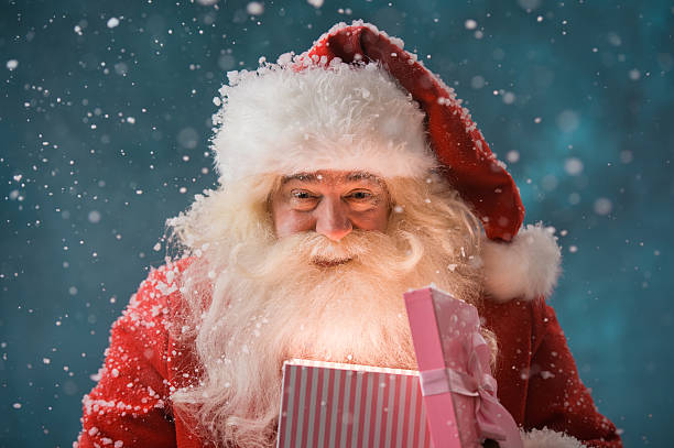 Happy Santa Claus opening his Christmas gift at North Pole stock photo