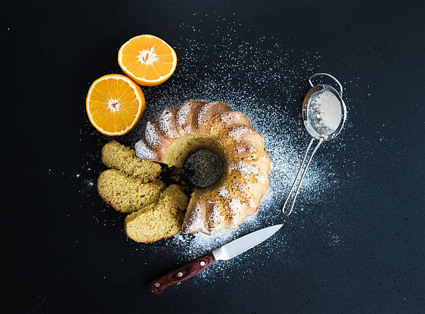 Moist orange bundt yoghurt cake with sugar powder, dark grunge background. Top view