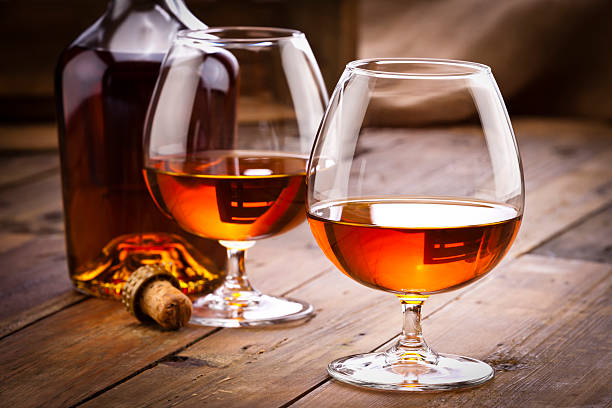 Cognac snifters with bottle on rustic wood table stock photo