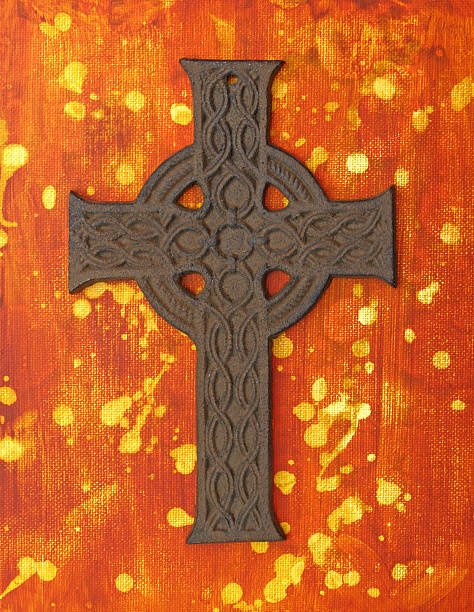 istock Rusted metal Celtic Cross on a painted orange yellow background 488430126