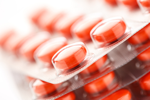 Red tablets in plastic packing as background