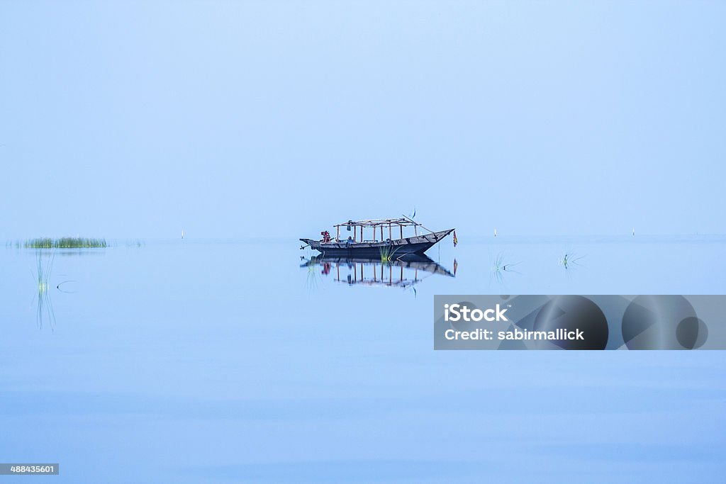 Lone Fishing Boat A solitary boat reflected in calm blue water. Odisha Stock Photo