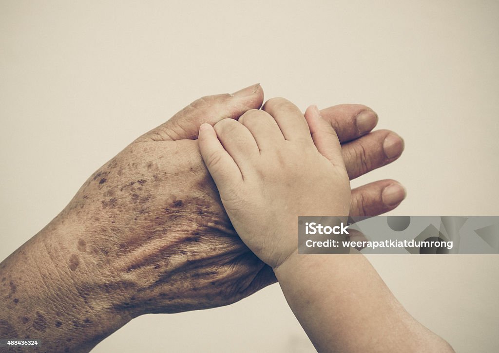Family love hand of a young baby touching old hand of the elderly - Love between young and old generation concept Grandparent Stock Photo