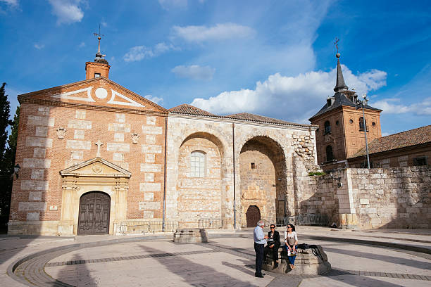 Ancient church in Alcala de Henares Alcala de Henares, Spain - April 14, 2014: Three tourists take a rest close to the ancient church of Santa Maria la Mayor, a temple built in 15th century by Don Pedro Diaz de Toledo in the old town of the city. alcala de henares stock pictures, royalty-free photos & images