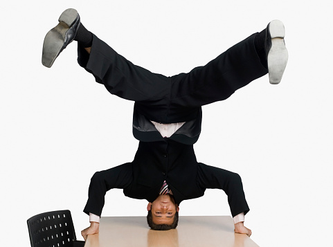 Businessman doing headstand on a conference table